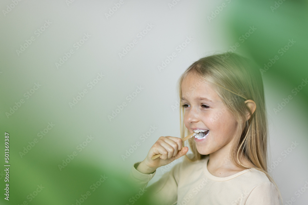 Cute little girl holding hands eco bamboo toothbrush on beige background. Sustainable living concept. Save the Planet for our children Cute little girl holding hands eco bamboo toothbrush on beige background. Sustainable living concept. Save the Planet for our children