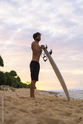 Sexy surfer surfing man with surfboard. Handsome young male athlete holding surf board with wet hair on summer beach sport holiday. Sports travel destination. Surfing lifestyle.