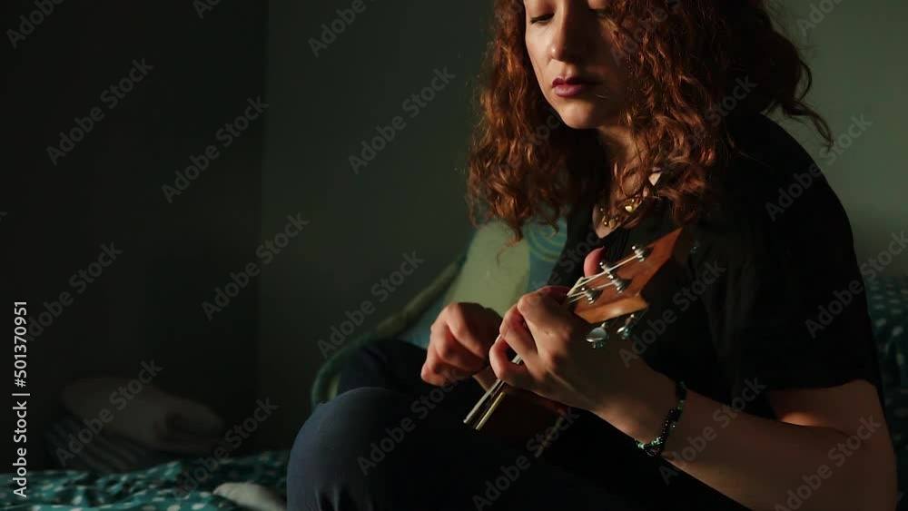 Mujer tocando el ukulele y cantando en su habitación. Concepto de musica.