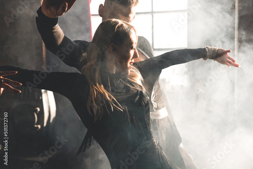 Couple of two professional ballroom dancers is dancing on loft studio. Beautiful art performance with heavy smoke. Sport life concept. Passion and emotional dance.