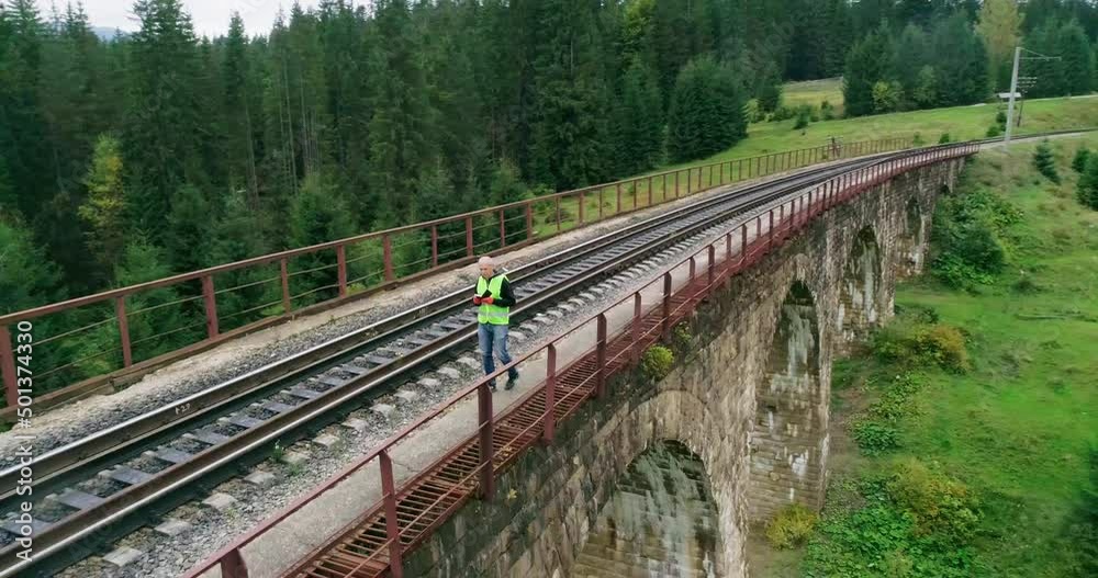 Aerial shot construction worker on railways. Work on railway. Old railway bridge over a river. Engineer work on railway. Engineer walking and check track work on railways. People walk on railway Aerial shot construction worker on railways. Work on railway. Old railway bridge over a river. Engineer work on railway. Engineer walking and check track work on railways. People walk on railway