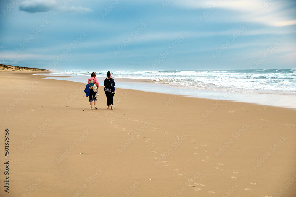 Couple of women walking along the deserted beach Couple of women walking along the deserted beach