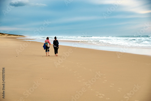 Couple of women walking along the deserted beach