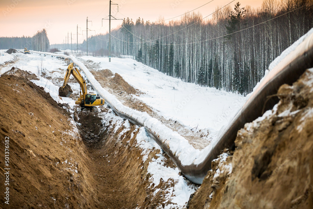Excavator digs a trench for laying a natural gas pipeline in a frost ...