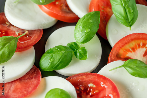 Caprese, light snack of tomatoes, mozzarella, olive oil and basil, close-up, selective focus.