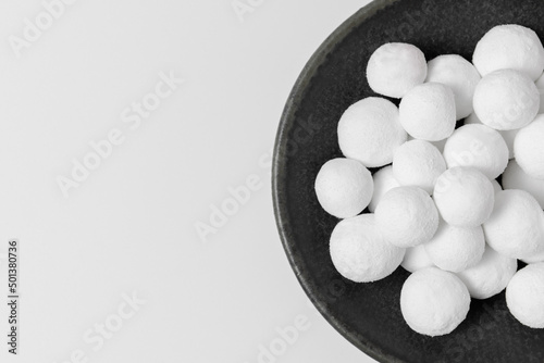 White sugar balls on a gray ceramic plate isolated on a white background. Close-up  top view  copy space.