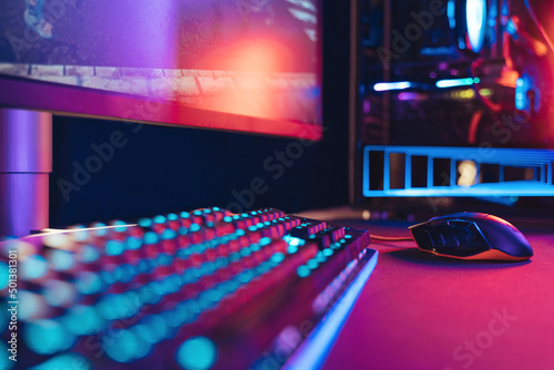 Close-up of professional gaming setup laying on desktop in neon lights. Gaming studio equipment are ready for online competition, tournament, e-sport event. Selective focus. Cyber sport, e-sport photo