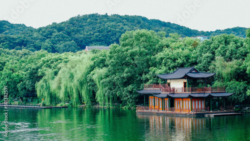 Traditional Chinese building on the shore of Westlake in Hangzhou surrounded forested mountains photo