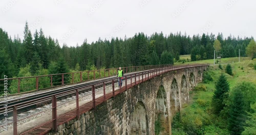Aerial shot construction worker on railways. Engineer work on railway. An Engineer walking on railways with inspection railroad under maintenance period. Old railway bridge over a river
