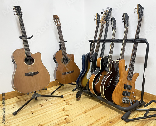 different electric guitars, bass guitars, acoustic and classical guitars on stand