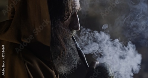 Wall Mural Happy aged monk smoking pipe in cave