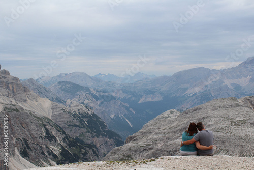 Back view of a couple hugging sitting in a mountainous landscape