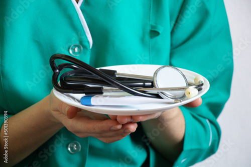 The doctor holds in his hands a stethoscope and a thermometer in a plate, health and medicine, ambulance