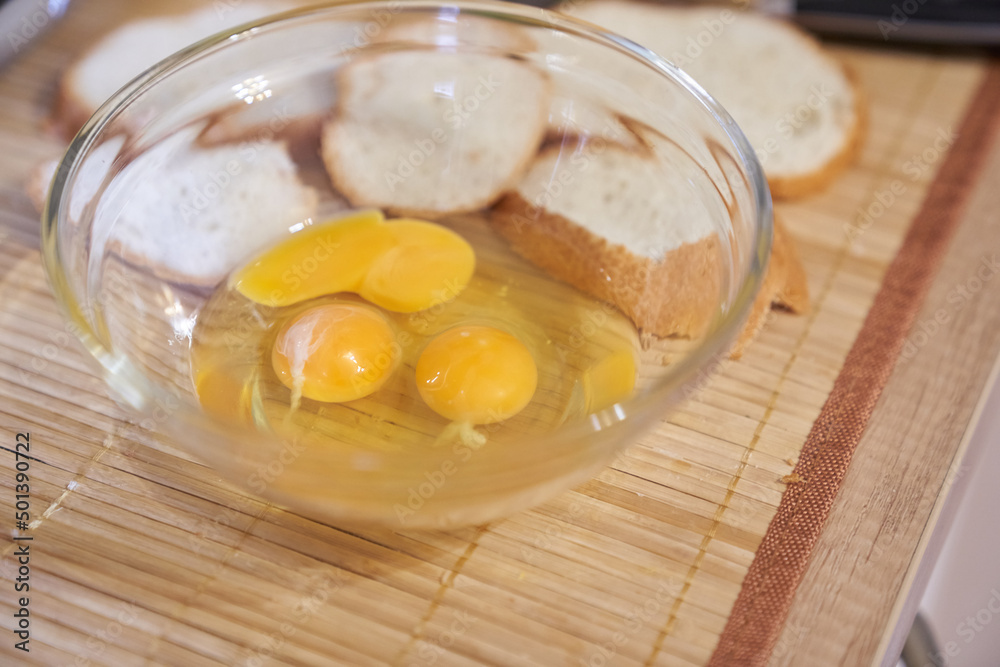 Close-up of three raw eggs in a clear glass bowl on the kitchen table with white bread. Step-by-step cooking of eggs for breakfast. High quality photo Close-up of three raw eggs in a clear glass bowl on the kitchen table with white bread. Step-by-step cooking of eggs for breakfast. High quality photo