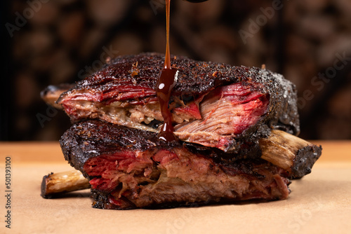 Closeup shot of a sauce pouring on smoked pork ribs on a wooden board