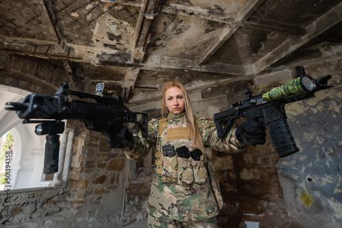 Caucasian woman in army uniform holding two machine guns. 