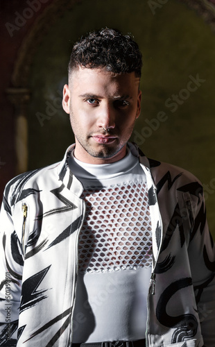Studio portrait of a young man with direct light with shadows. Fashion trendy studio photo shoot with trendy clothes and isolated with black background photo