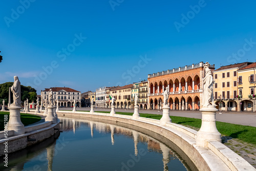 Scenic view on Prato della Valle, square in the city of Padua, Veneto, Italy, Europe. Green island at center, Isola Memmia surrounded by canal bordered by two rings of statues. Reflection in water