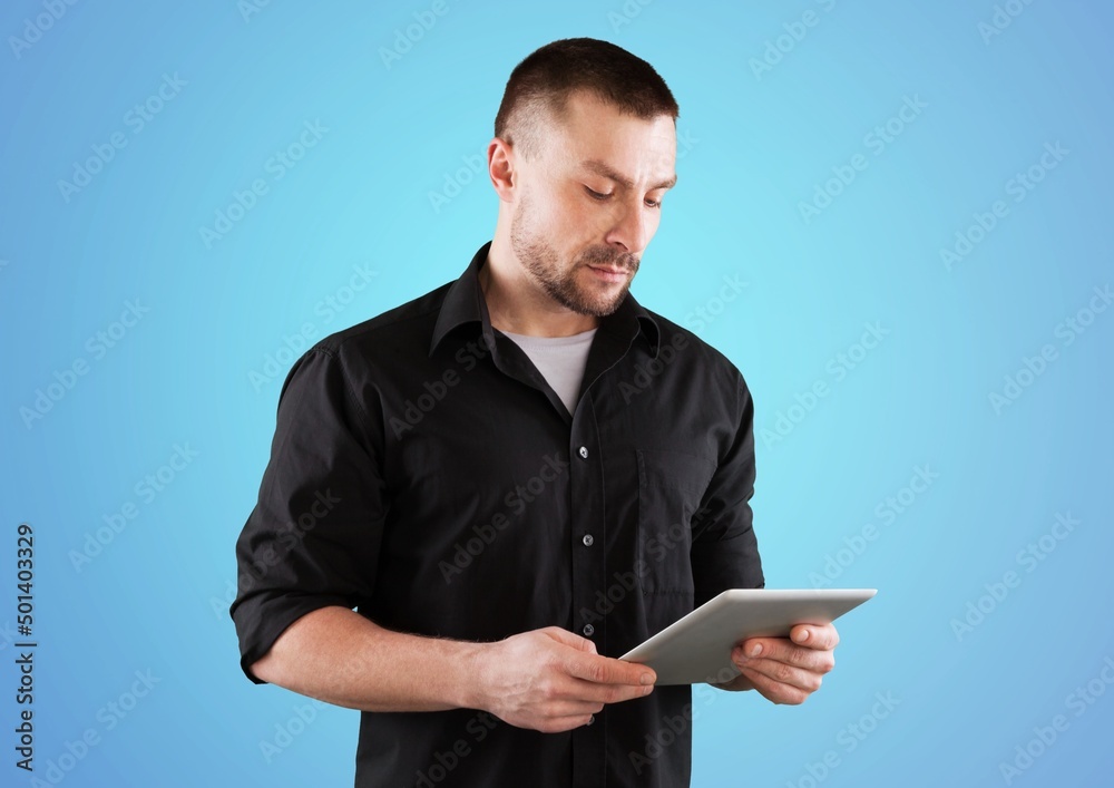 Happy man using digital tablet on blue background. Smiling student guy holding pad remote learning in app. Happy man using digital tablet on blue background. Smiling student guy holding pad remote learning in app.