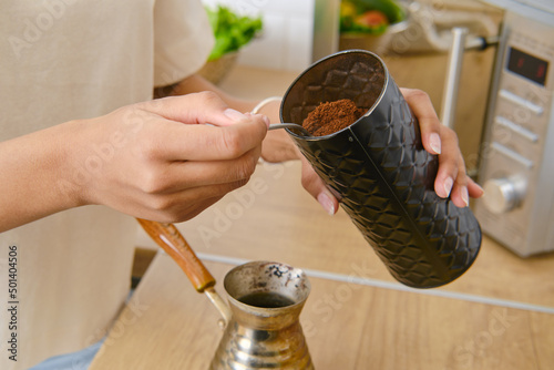 Closeup view of making ground coffee at home in turkish cezve photo