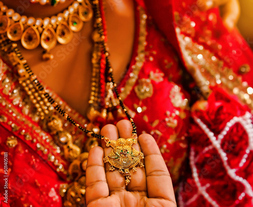 The hand of the groom holding the Indian marriage necklace after tied it around the bride's neck photo