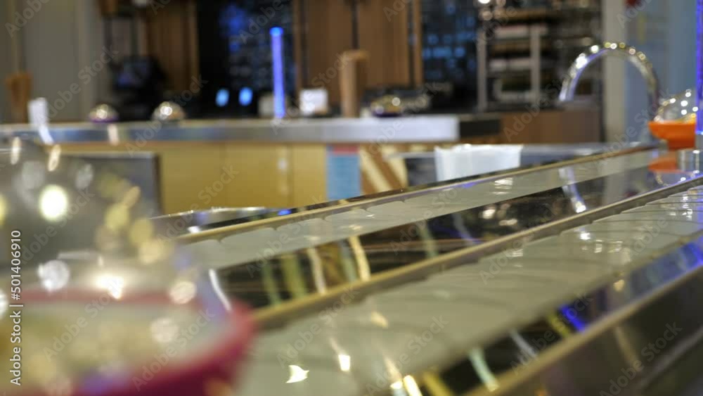 Japanese restaurant with sushi and rolls moving on plates on rotating conveyor belt. Nobody Japanese restaurant with sushi and rolls moving on plates on rotating conveyor belt. Nobody