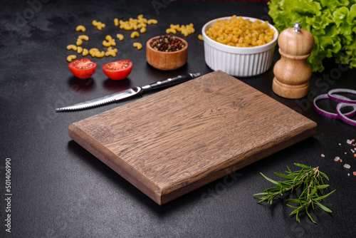 Vászonkép A wooden cutting board with a kitchen knife with spices and herbs