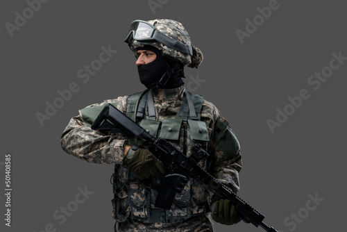 Obraz na plátně Shot of proud infantry dressed in protective costume holding rifle isolated on gray background