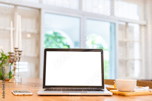 Mockup of laptop computer with empty screen with coffee cup and smartphone on table of the coffee shop background,White screen