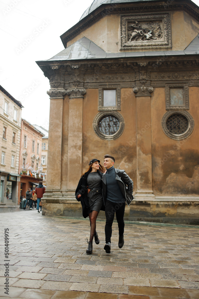 Modern couple running down the street of the old city. Lviv, Ukraine November 2, 2019