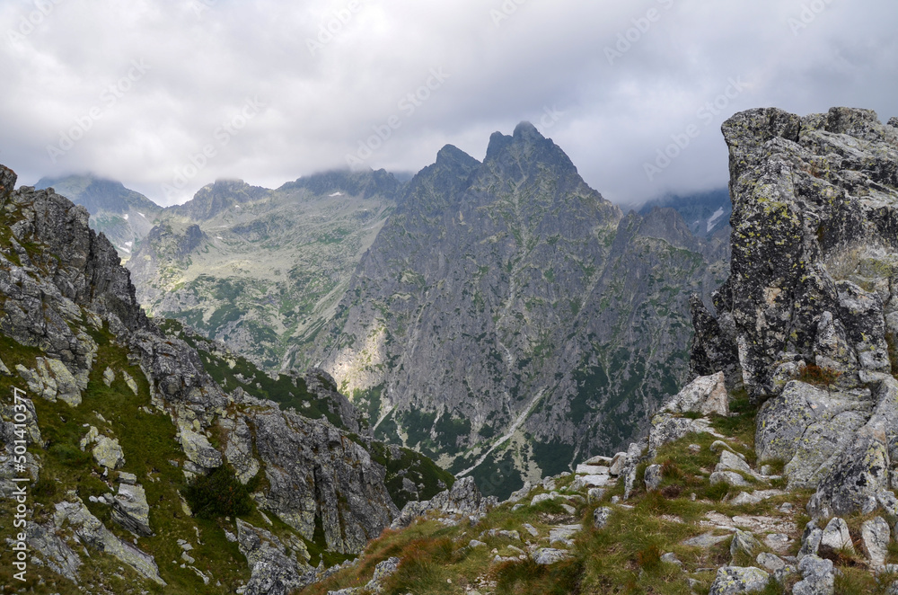 Landscape with rocky mountain ridge and sharp peaks hidden by clouds. High Tatras, Slovakia
