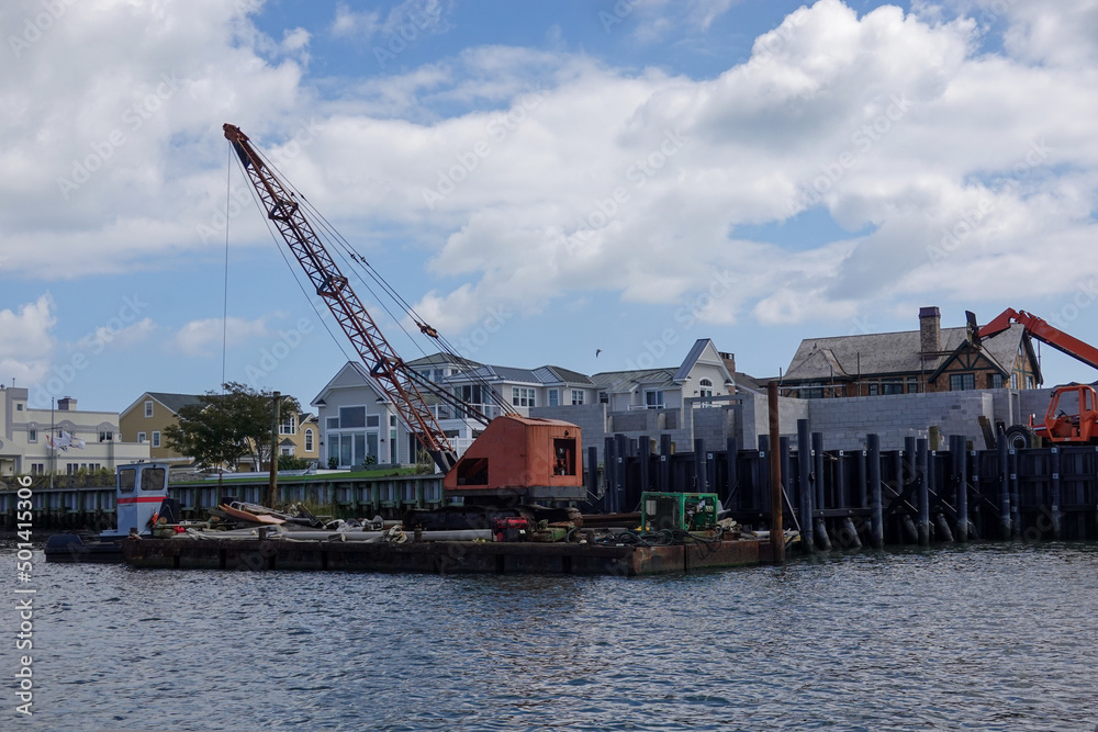 Large crane on a barge on a bay near a sea wall