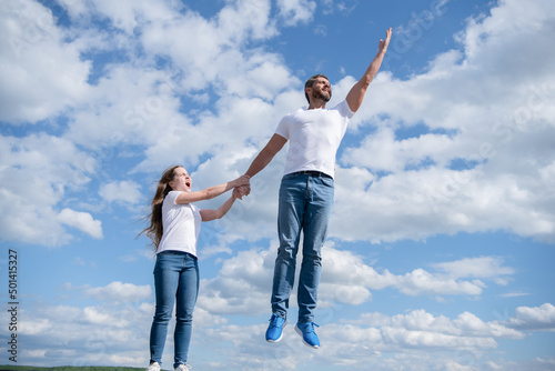 daughter hold her dad jumping in sky