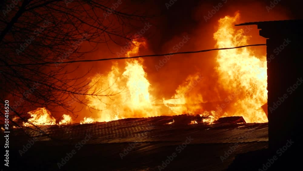 fire on the roof of the house. a burning at building house close-up. home insurance apartment concept. huge fire blazes houses and trees 911 night. property damage arson protection