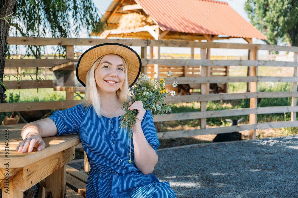 Cottages at Summer Village, Vacation Rentals. Domestic Travel, Local Travel, Summer Country Travel. Countryside Getaways. Young woman in straw hat enjoys summer vacation at the farm