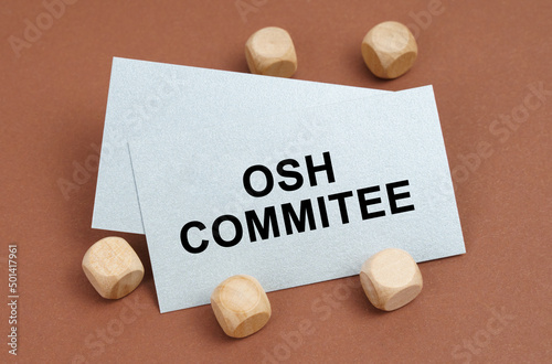 On a brown surface, wooden cubes and a business card with the inscription - OSH Commitee