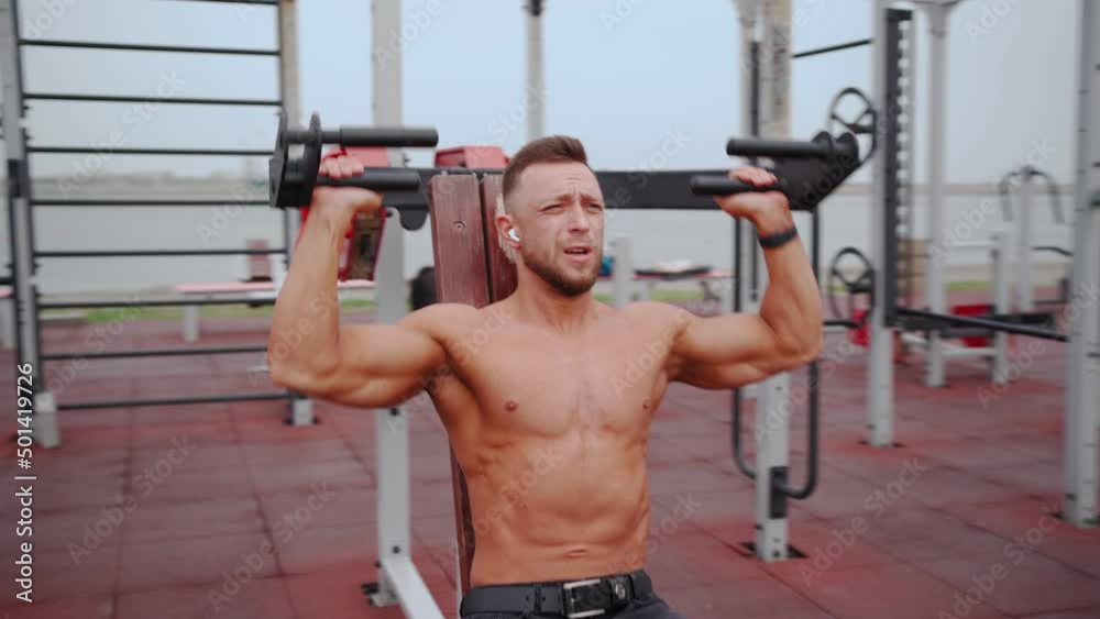 Muscular Man Trains the Muscles of the Shoulders on a Special Simulator in the Outdoor Area. Healthy Lifestyle, Wellbeing. Sports and Workout. Fitness and Bodybuilding Concept. 