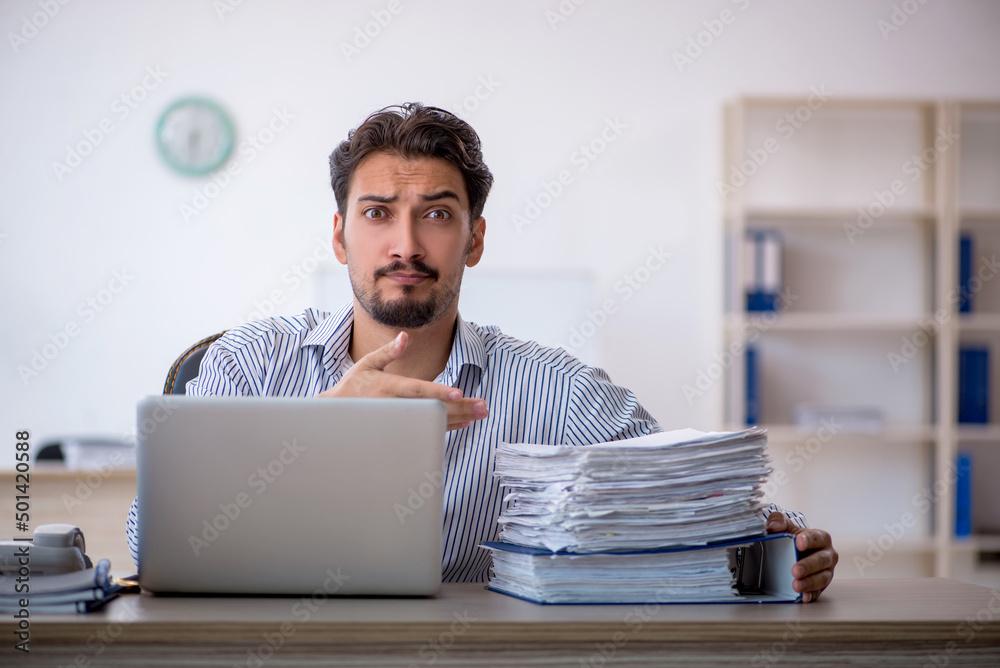 Young male employee and too much work in the office Young male employee and too much work in the office