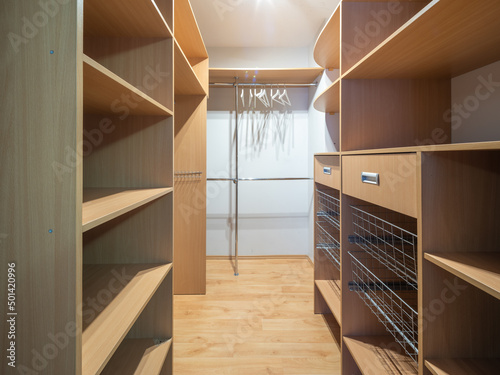 Empty wardrobe cloackroom in luxury apartment. Wooden shelves.