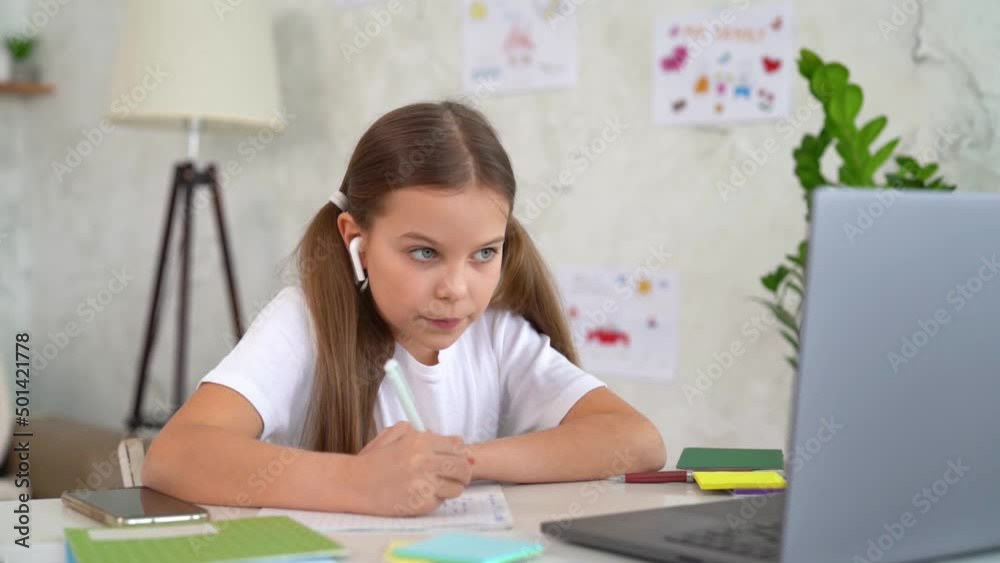 Remote school lessons. Child smiles studies and gets knowledge remotely. Little girl study online at home does homework. Distance learning education. Quarantine and Social distancing concept. Remote school lessons. Child smiles studies and gets knowledge remotely. Little girl study online at home does homework. Distance learning education. Quarantine and Social distancing concept.