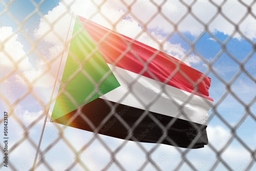 A steel mesh against the background of a blue sky and a flagpole with the flag of sudan A steel mesh against the background of a blue sky and a flagpole with the flag of sudan