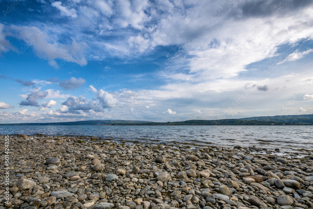 Seeufer Bodensee mit Steinen blauer Himmel und schönen Wolken 