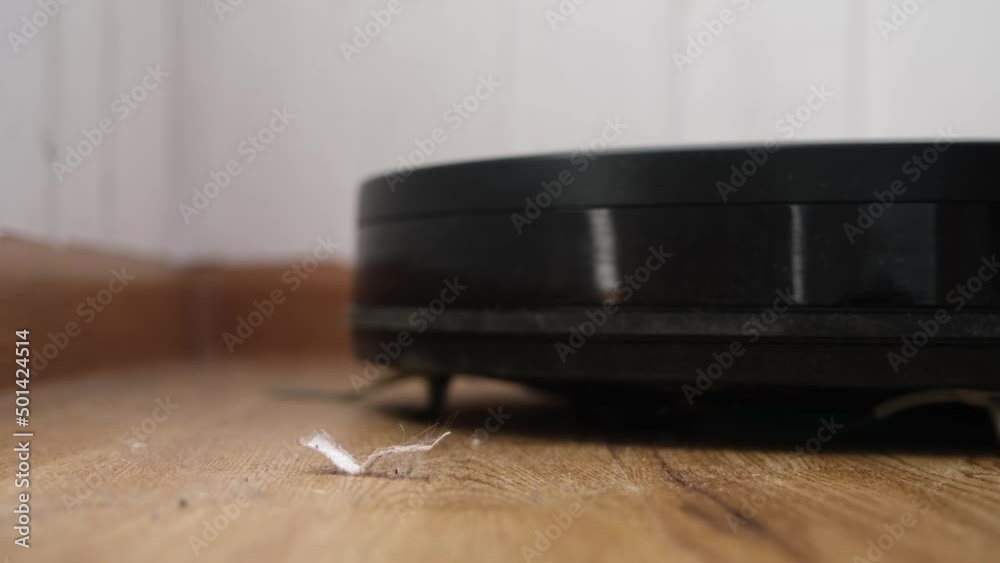 Robot vacuum cleaner cleans dust and debris on the floor. Black robot, slow motion Robot vacuum cleaner cleans dust and debris on the floor. Black robot, slow motion