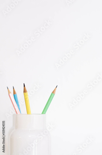 flower vase used to store some pencils, there is a blue, a pink, a green and a yellow pencil. four wooden pencils in a white glass © GonzaloVega