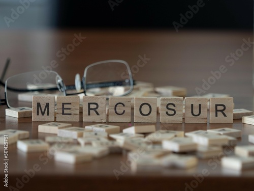 mercosur word or concept represented by wooden letter tiles on a wooden table with glasses and a book photo