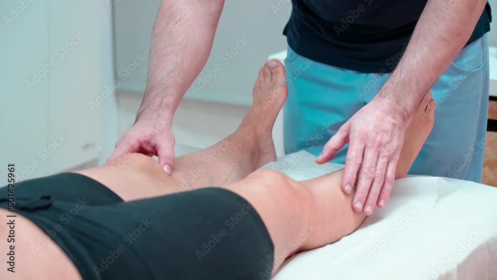Caucasian specialist osteopath chiropractor checks woman's leg joints for ligament injuries. In the clinic. Caucasian specialist osteopath chiropractor checks woman's leg joints for ligament injuries. In the clinic.