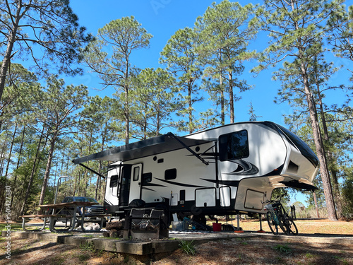 A fifth wheel trailer and campsite in the woods.