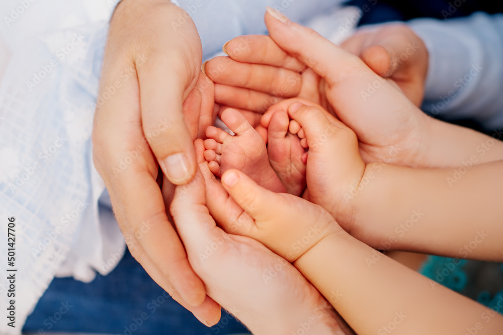 winzige Füße eines Neugeborenen in den Händen liebevoller Eltern - obrazy, fototapety, plakaty 