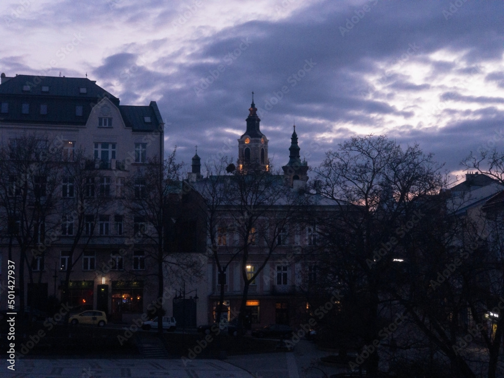Obraz premium Twilight colours of night Przemysl at Poland at Wladycze street. View is from museum of bells and tobacco pipes to the lights of bell tower and clock near Roman Catholic archicathedra in the Gothic 