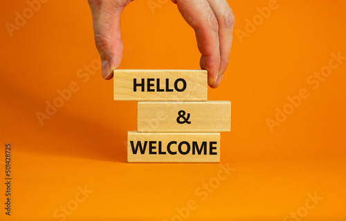 Hello and welcome symbol. Concept words Hello and welcome on wooden blocks. Businessman hand. Beautiful orange table orange background. Business hello and welcome concept. Copy space. photo